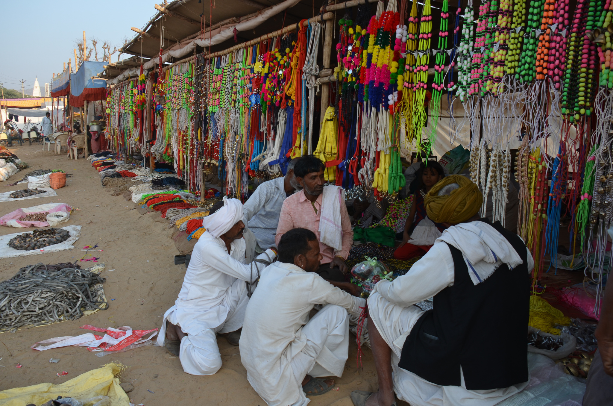 Vibrant market scene in Pushkar showcasing colorful decorations and accessories, with locals engaged in conversation.