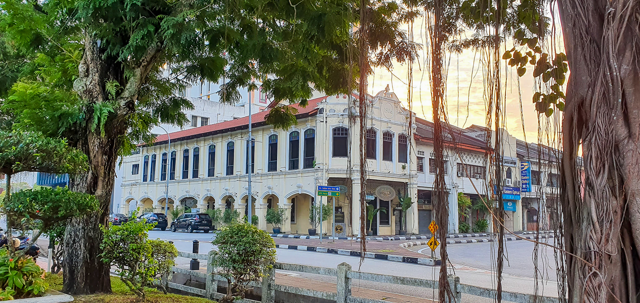 Historic building with colonial architecture in Ipoh, framed by greenery and a beautiful sky.