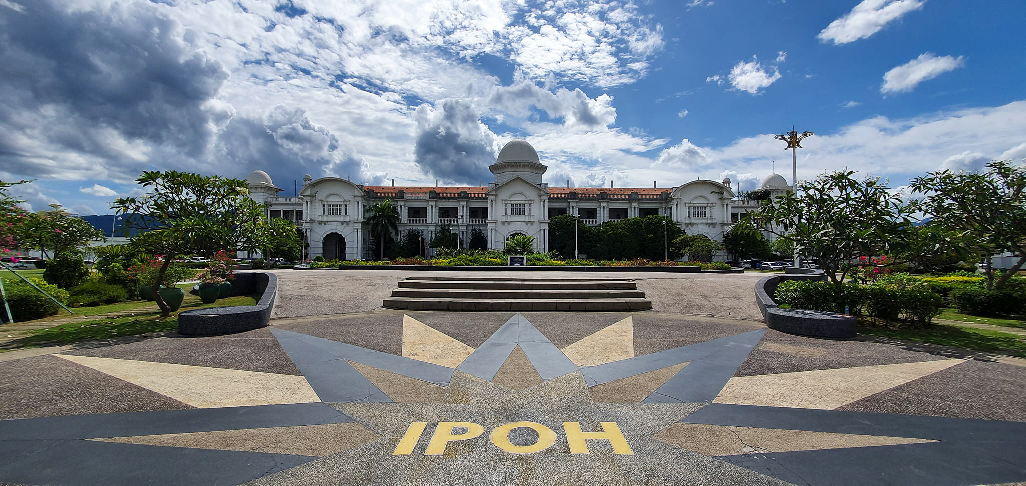 View of the Ipoh Railway Station in Malaysia, showcasing its grand architectural design against a cloudy sky.