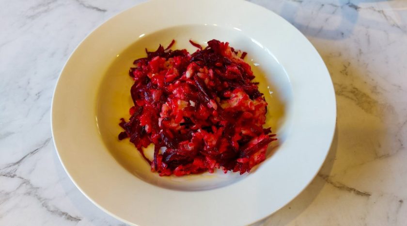 Richly deep in colour, a plain white bowl of creamy red beetroot risotto