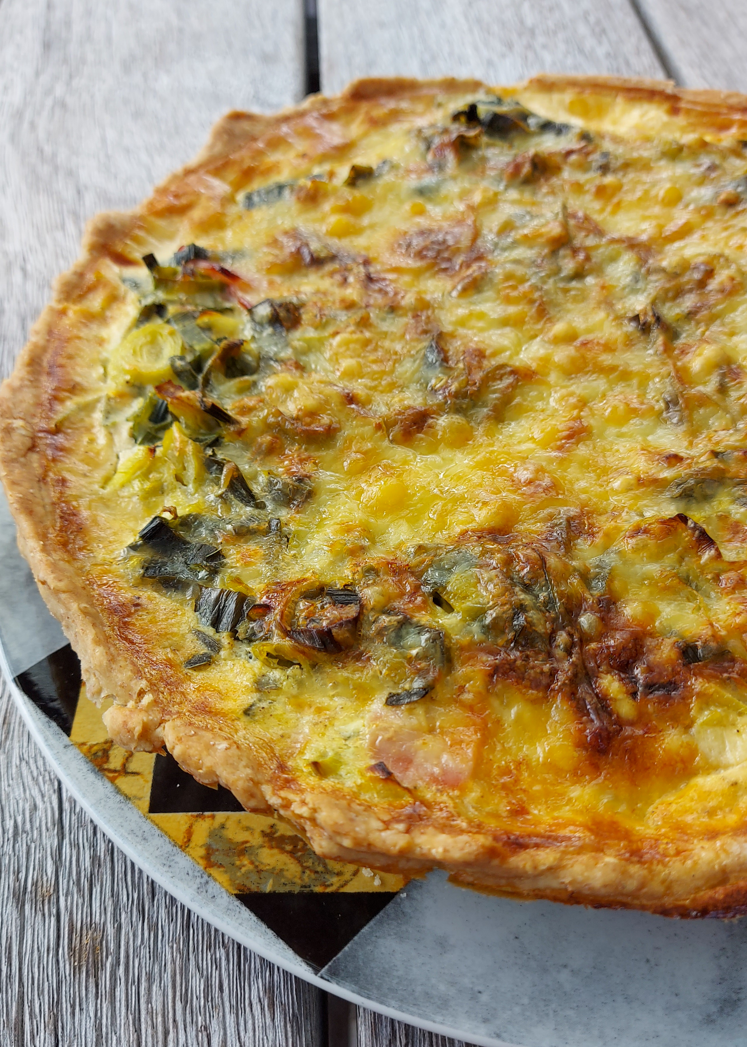 A homemade Ham and Leek Quiche with olive oil pastry, ready to be served with a side salad