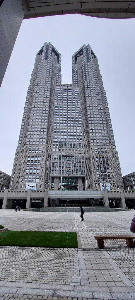 View of the Tokyo Metropolitan Government Building, showcasing its impressive twin towers and modern architectural design against a cloudy sky.