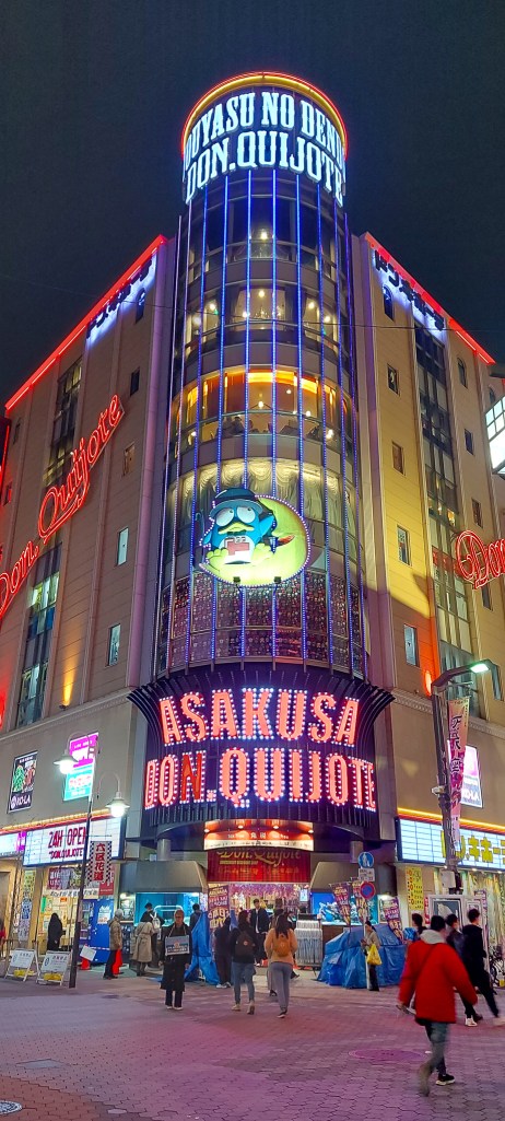 Brightly lit exterior of the Don Quijote store in Asakusa, featuring vibrant signage and a lively street scene at night.